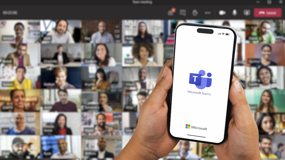 Boy holding a smartphone iPhone 14 Pro with Microsoft Teams app on the screen. 