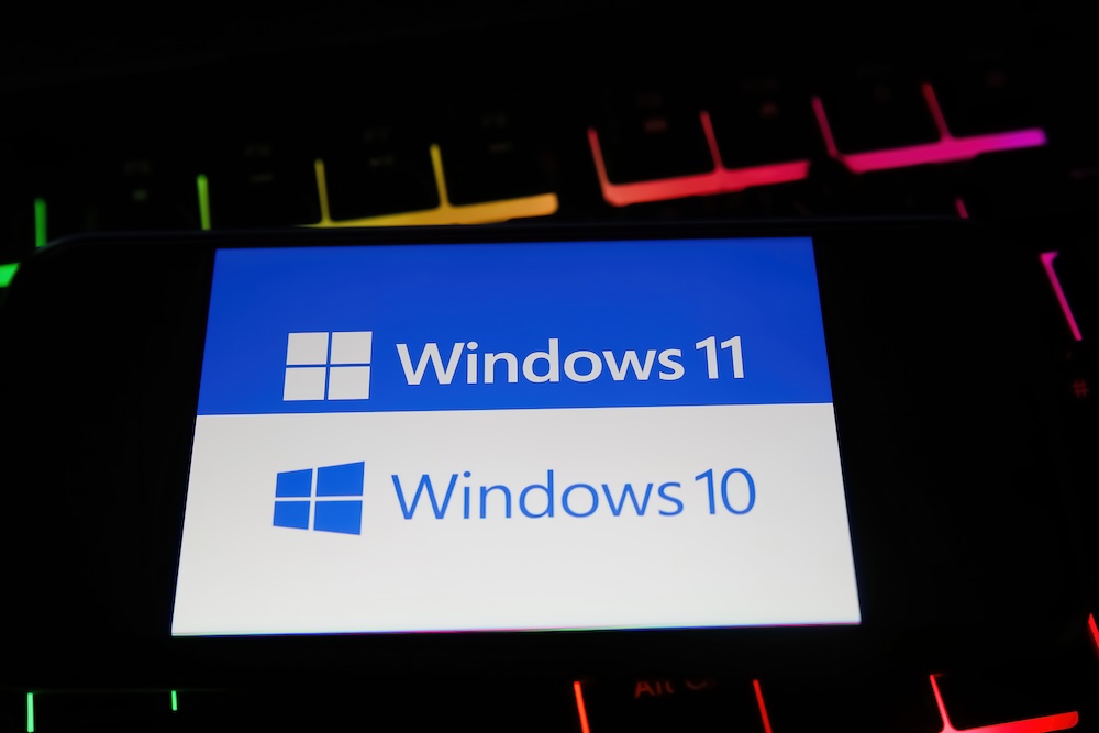 Closeup of mobile phone with logo lettering of windows 10 and 11 operating system on computer keyboard